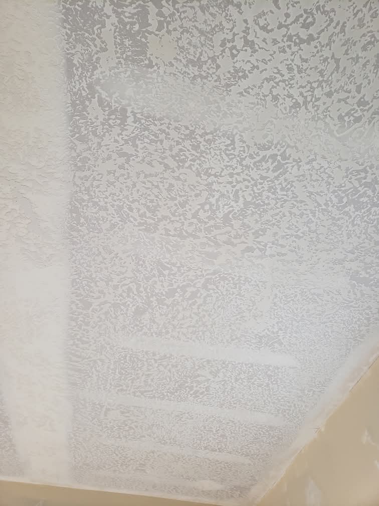 White ceiling with heavy knockdown texture featuring uneven patches and horizontal repair stripes.