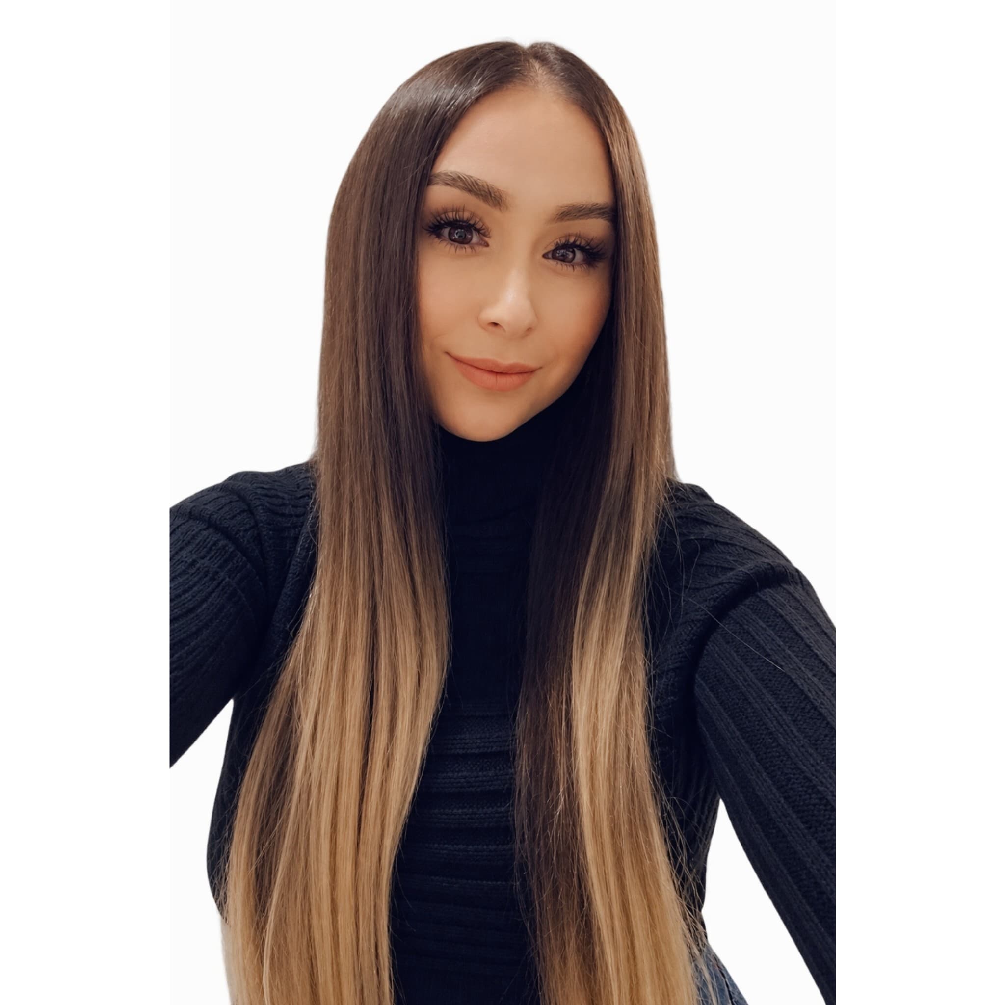 Woman with long, straight brown and blonde ombré hair wearing a black ribbed turtleneck sweater.