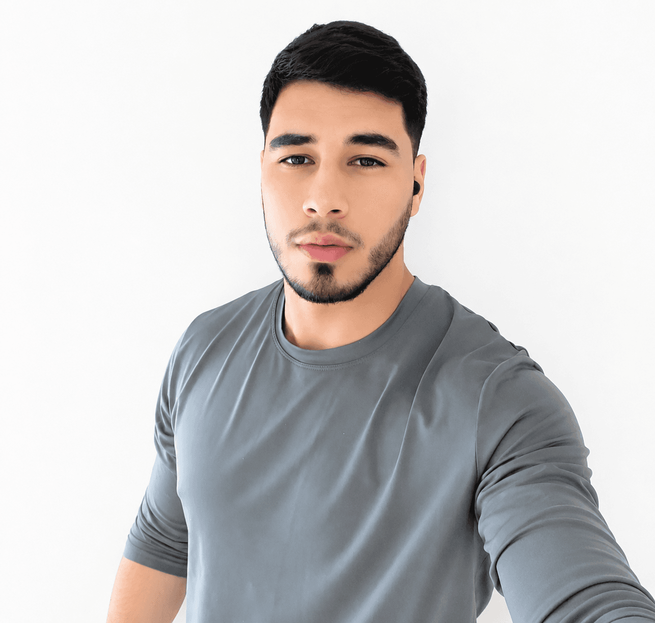 Bearded young man in a gray long-sleeved athletic shirt posing against a white background.